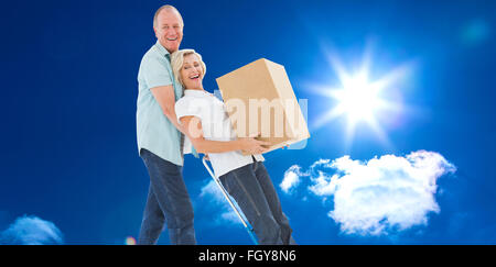 Image composite de plaisir vieux couple holding moving boxes Banque D'Images