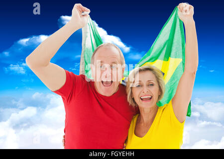 Libre de vieux couple cheering at camera holding drapeau Brésil Banque D'Images