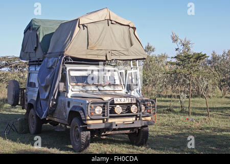 Vieux Land Rover Defender 110 garé dans un parc national du Kenya. Tentes de toit pitched Banque D'Images