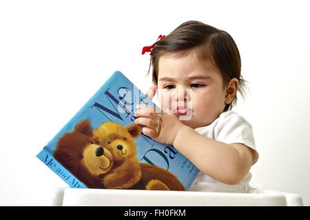 Onze mois bébé fille jouant avec un livre Banque D'Images