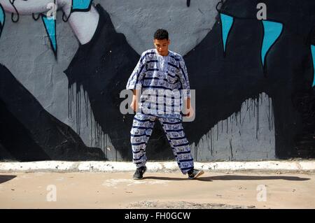 Jeune homme Syrian-Moroccan danses de rue en costume africain en face de l'art de mur downtown Banque D'Images