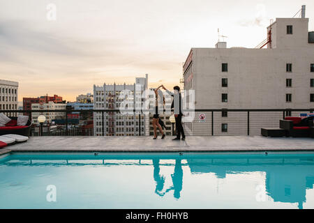 Un couple danse près de la piscine sur le toit avec vue sur le paysage urbain du centre-ville de Los Angeles, Californie. Banque D'Images