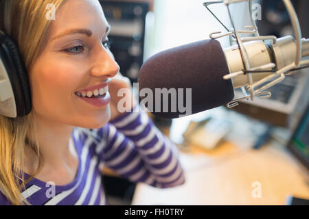 Happy young female animateur de radio broadcasting in studio Banque D'Images