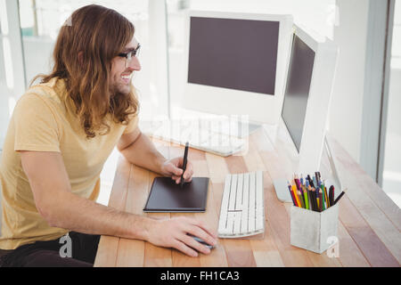 Hipster heureux avec tablette graphique looking at computer Banque D'Images