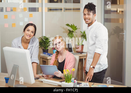 Portrait of smiling business people pointe vers computer in office Banque D'Images