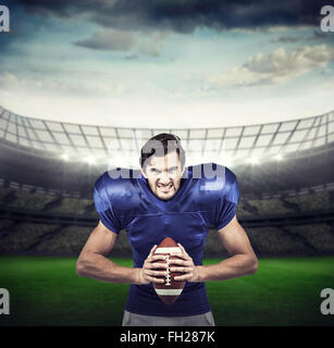 Image composite de l'agressivité american football player holding ball Banque D'Images