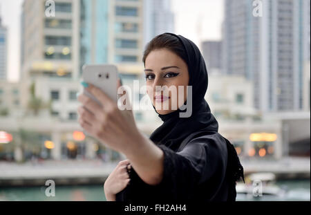 Belle jeune femme emiratis en tenant avec son smartphone selfies Banque D'Images