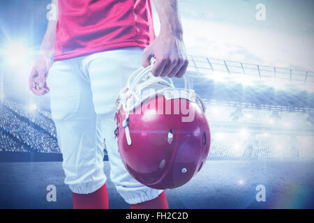 Image composite d'un joueur de football américain en tenant son casque sur sa main Banque D'Images