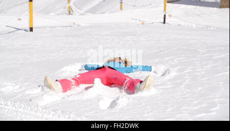 Jeune femme faisant un ange dans la neige blanche Banque D'Images