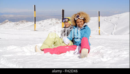 Couple assis dans la neige sur la pente de ski Banque D'Images