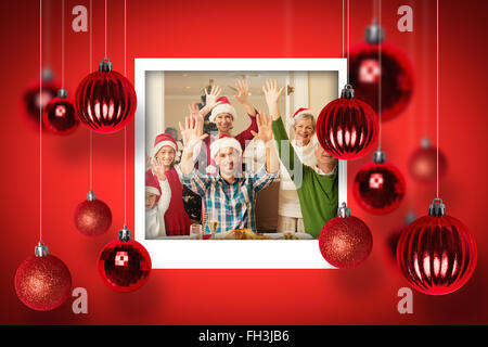 Image composite de extended family in santa hat cheering at camera Banque D'Images