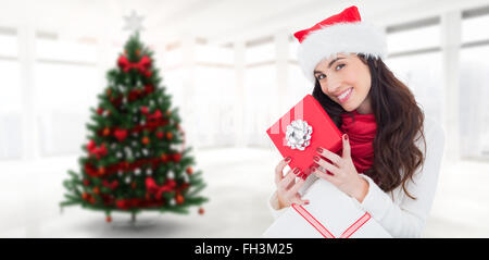 Image composite de smiling brunette holding christmas gifts Banque D'Images