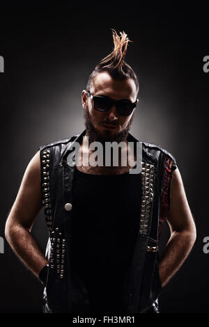 Shot vertical d'un jeune homme punk avec un Mohawk hairstyle sur fond sombre Banque D'Images