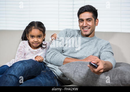 Smiling père regardant la télévision avec sa fille sur le canapé Banque D'Images