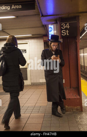 Homme juive hassidique textes comme il attend de la F Train à la 34e rue à Manhattan, New York. Banque D'Images