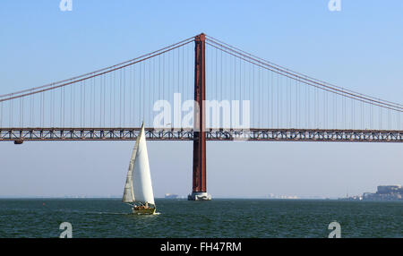 Lisbonne, Portugal. 14 Décembre, 2015. Un bateau à voile sur le Tage à l'avant de la Ponte 25 de Abril Bridge à Lisbonne, Portugal, le 14 décembre 2015. Le pont est le deuxième plus long pont suspendu, après le Pont de Tsing Ma à Hong Kong, et assure les trafics ferroviaire et routier. Photo : Hauke Schroeder/dpa/Alamy Live News Banque D'Images