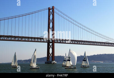 Lisbonne, Portugal. 14 Décembre, 2015. Bateaux à voile à partir de la BMW Sailing Academy sur le Tage à l'avant de la Ponte 25 de Abril Bridge à Lisbonne, Portugal, le 14 décembre 2015. Le pont est le deuxième plus long pont suspendu, après le Pont de Tsing Ma à Hong Kong, et assure les trafics ferroviaire et routier. Photo : Hauke Schroeder/dpa/Alamy Live News Banque D'Images