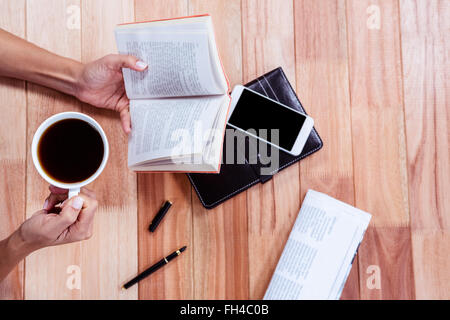 Frais généraux de mains féminines tenant un livre et du café Banque D'Images