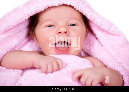 Close-up portrait of laughing smiling bébé nouveau-né sur une serviette en tissu éponge rose Banque D'Images