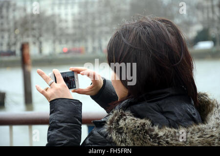 Une femme prend une photo sur son iPhone. Banque D'Images