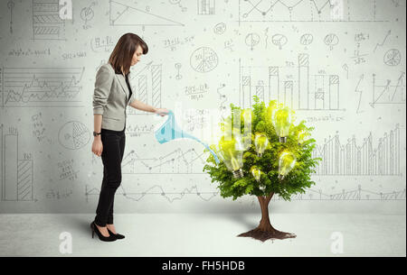 Business Woman déverser de l'eau sur les arbres de croissance ampoule Banque D'Images