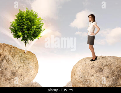 Businesswoman on rock mountain avec un arbre Banque D'Images