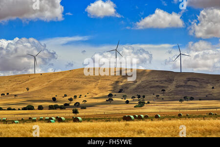 Chaîne des éoliennes sur win haut haut de collines en bruissement de l'Australie. Région rurale avec des fermes cultivées et meules fournissant la masse Banque D'Images