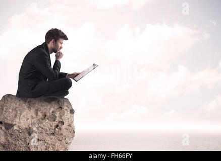 Business man sitting on stone edge Banque D'Images