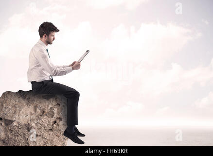 Business man sitting on stone edge Banque D'Images