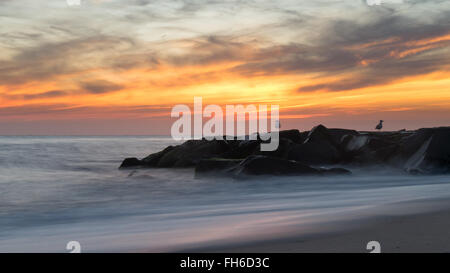Bien s'estomper après une belle journée chaude sur la plage. L'écoulement de l'eau est complété par un ciel intensément colorés. Banque D'Images