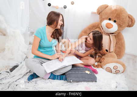 Deux belles soeurs joyeux le dessin et s'amuser dans la chambre des enfants Banque D'Images