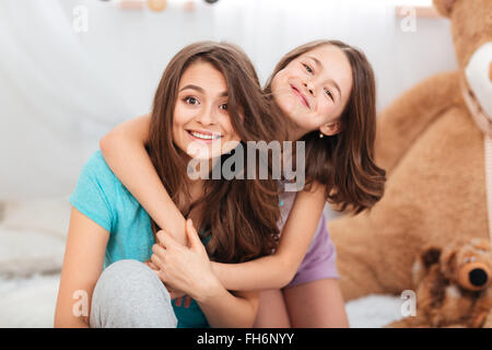 Portrait de deux sœurs belle heureux assis et hugging at home Banque D'Images