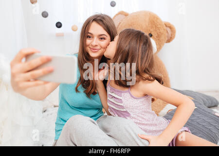 Deux jolies father kissing et décisions en selfies chambre enfants Banque D'Images