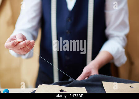 Mains d'adapter avec aiguille et fil vêtements couture Banque D'Images