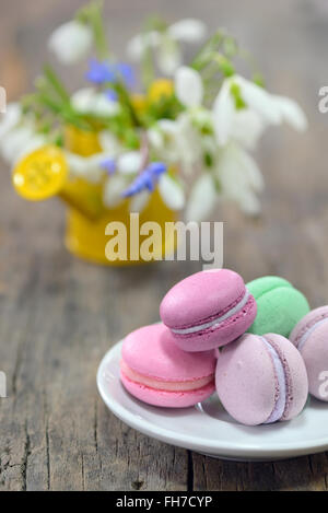 Macarons Français colorés et de fleurs printanières sur fond de bois Banque D'Images