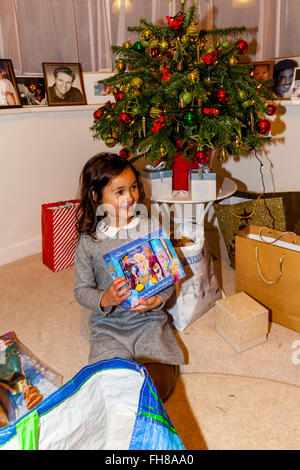 Une race mixte enfant ouvrant ses cadeaux de Noël Le Jour de Noël, Brighton, Sussex, UK Banque D'Images