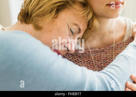 Senior woman with closed eyes appuyé contre l'épaule de la jeune femme Banque D'Images