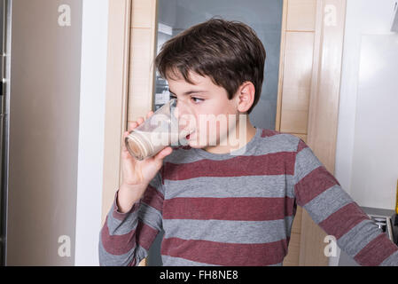 Jeune garçon de boire un verre de lait au chocolat Banque D'Images