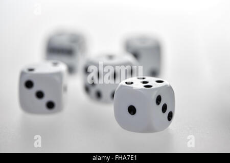 Cinq dés de blanc avec des yeux noirs sur une table en verre blanc Banque D'Images