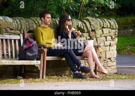 Jeune couple assis sur un banc, profitant du soleil. Banque D'Images