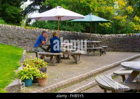 Le Northumberland. Couple assis à une table de pique-nique sous un parasol. Le Moine Blanc de thé, Blanchland. Banque D'Images