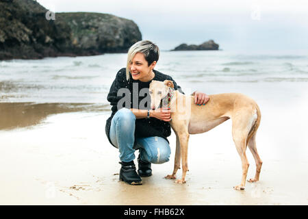 L'Espagne, Llanes, happy young woman with her Greyhound sur la plage Banque D'Images