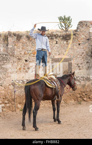 Un Mexicain charro ou pratiques cowboy roping compétences sur son cheval à une hacienda ranch dans Alcocer, au Mexique. La Charreada est une forme traditionnelle mexicaine de rodeo et teste les compétences de l'équitation à cowboy au lasso, et le contrôle du bétail. Banque D'Images