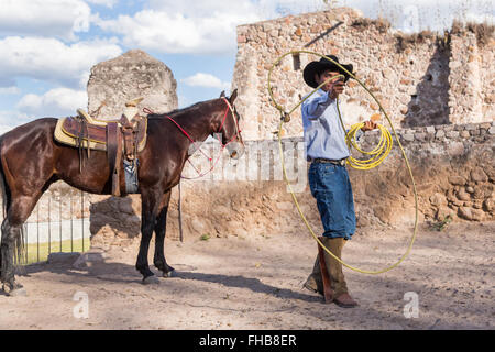 Un Mexicain charro ou pratiques cowboy roping compétences avec son cheval à une hacienda ranch dans Alcocer, au Mexique. La Charreada est une forme traditionnelle mexicaine de rodeo et teste les compétences de l'équitation à cowboy au lasso, et le contrôle du bétail. Banque D'Images