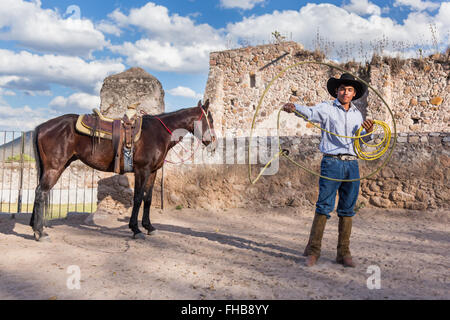 Un Mexicain charro ou pratiques cowboy roping compétences avec son cheval à une hacienda ranch dans Alcocer, au Mexique. La Charreada est une forme traditionnelle mexicaine de rodeo et teste les compétences de l'équitation à cowboy au lasso, et le contrôle du bétail. Banque D'Images