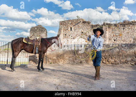 Un Mexicain charro ou pratiques cowboy roping compétences avec son cheval à une hacienda ranch dans Alcocer, au Mexique. La Charreada est une forme traditionnelle mexicaine de rodeo et teste les compétences de l'équitation à cowboy au lasso, et le contrôle du bétail. Banque D'Images