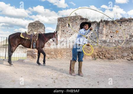 Un Mexicain charro ou pratiques cowboy roping compétences avec son cheval à une hacienda ranch dans Alcocer, au Mexique. La Charreada est une forme traditionnelle mexicaine de rodeo et teste les compétences de l'équitation à cowboy au lasso, et le contrôle du bétail. Banque D'Images