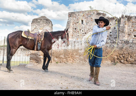 Un Mexicain charro ou pratiques cowboy roping compétences avec son cheval à une hacienda ranch dans Alcocer, au Mexique. La Charreada est une forme traditionnelle mexicaine de rodeo et teste les compétences de l'équitation à cowboy au lasso, et le contrôle du bétail. Banque D'Images