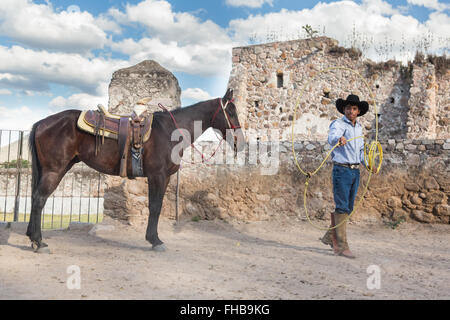 Un Mexicain charro ou pratiques cowboy roping compétences avec son cheval à une hacienda ranch dans Alcocer, au Mexique. La Charreada est une forme traditionnelle mexicaine de rodeo et teste les compétences de l'équitation à cowboy au lasso, et le contrôle du bétail. Banque D'Images