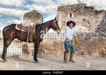 Un Mexicain charro ou pratiques cowboy roping compétences avec son cheval à une hacienda ranch dans Alcocer, au Mexique. La Charreada est une forme traditionnelle mexicaine de rodeo et teste les compétences de l'équitation à cowboy au lasso, et le contrôle du bétail. Banque D'Images